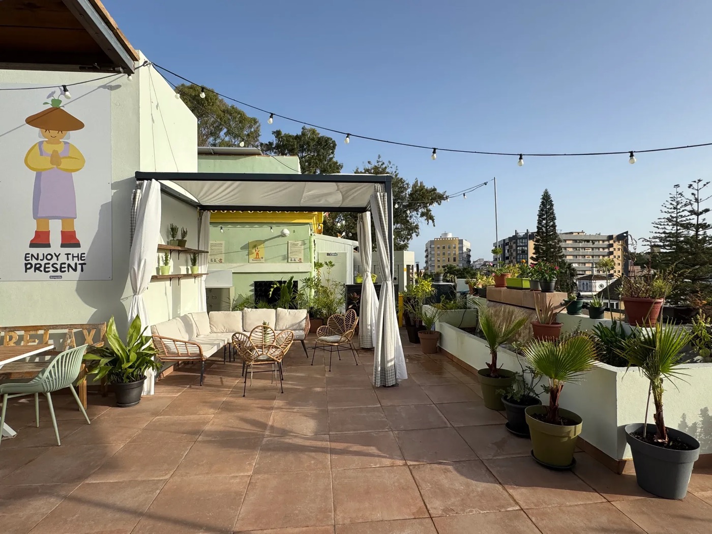 La terraza del rooftop con sofás, plantas y guirnaldas de luces